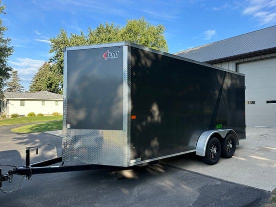 Charcoal tandem-axle enclosed cargo trailer with a silver front