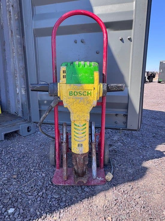Jack hammer mounted on a red two-wheel transport cart