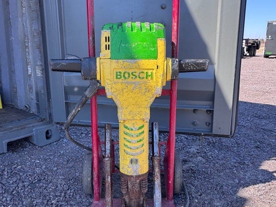 Jack hammer mounted on a red two-wheel transport cart