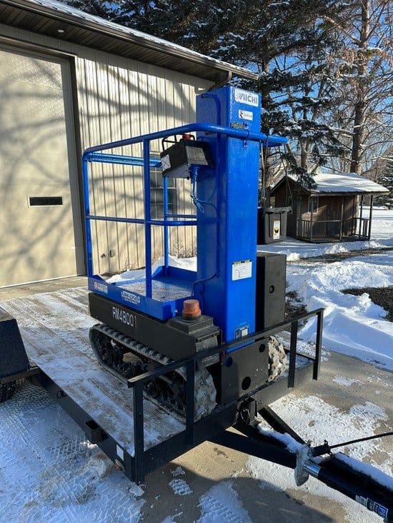 Blue tracked personal manlift loaded on a flatbed trailer