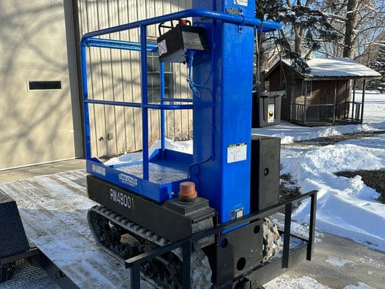 Blue tracked personal manlift loaded on a flatbed trailer