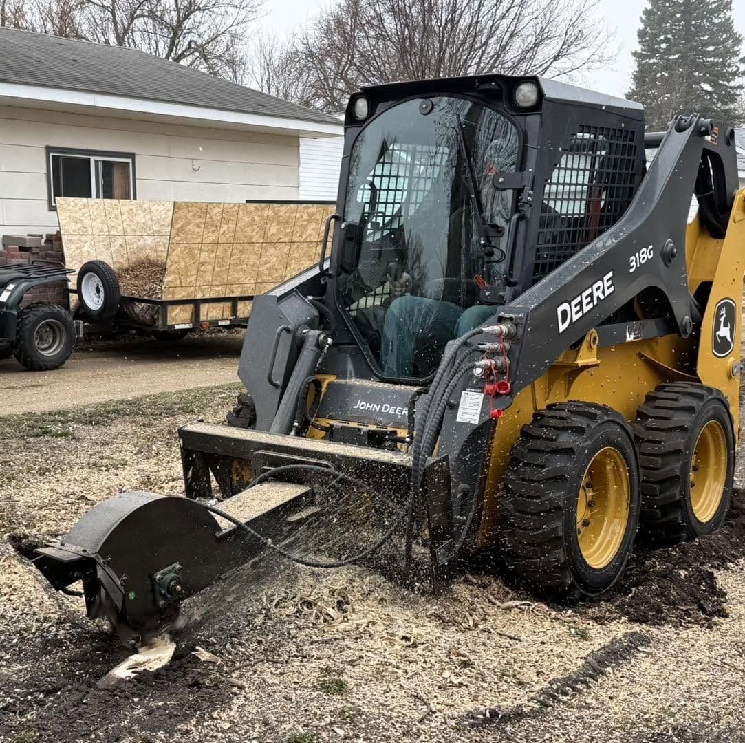 Hydraulic stump grinder attachment on a John Deere skid steer, grinding down a stump